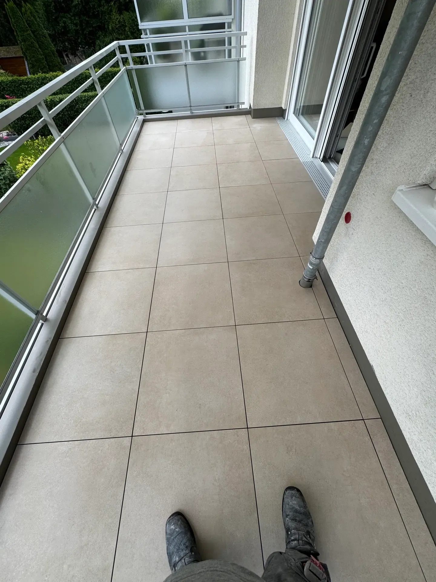 Fertig sanierter Balkon mit hellem Feinsteinzeug-Belag, Edelstahlgeländer und Sichtschutzelement
