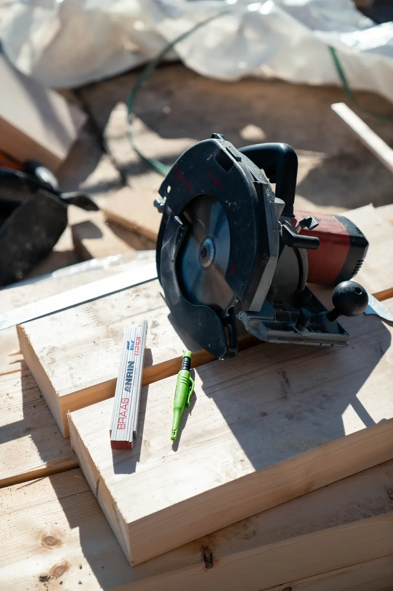Handkreissäge und Zollstock auf frisch zugesägten Holzbalken auf der Baustelle